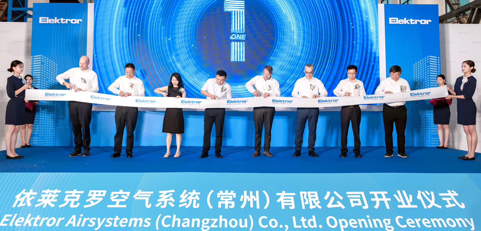 Official representatives of Elektror and the Chinese government cut a ribbon in front of an LED wall at the opening of the new Elektror plant in Changzhou.