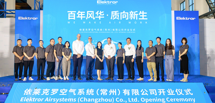 The new employees of the Elektror plant in Changzhou stand in front of an LED wall and look into the camera.